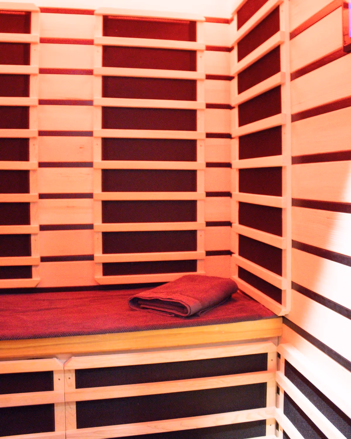Bench and folded towel inside the infrared sauna room at Sabél Studios